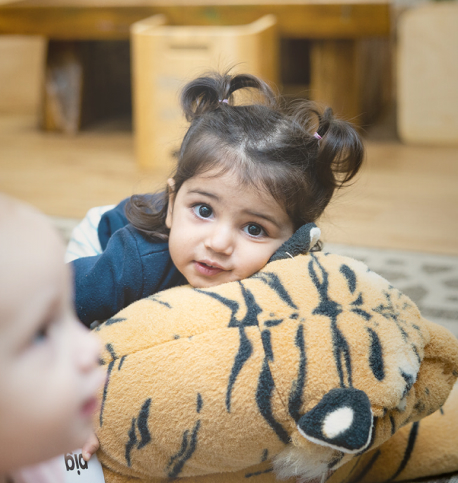 Column image Toddler lying on a soft tiger toy in a childcare centre