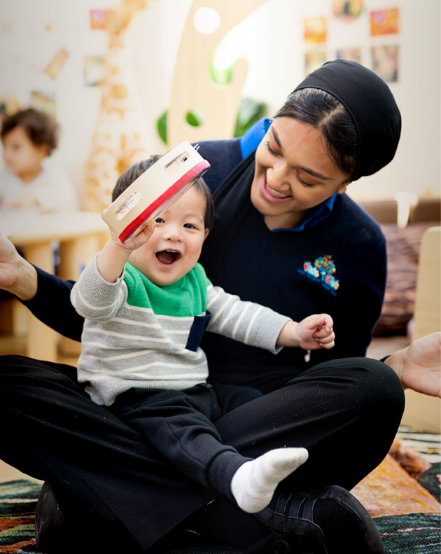 Carousel image Child at a day care centre sitting with a caregiver during a learning activity