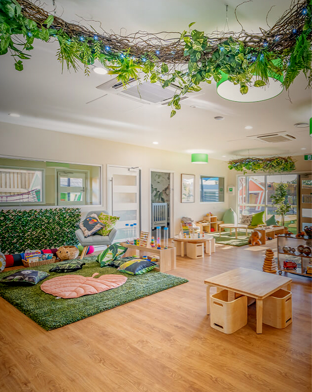 Column image Childcare playroom with hanging greenery, wooden furniture, soft play mats and natural learning spaces