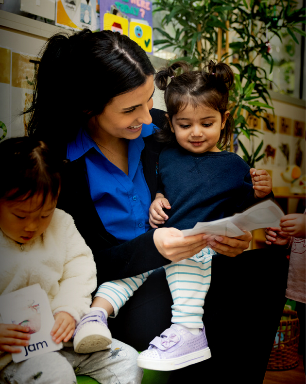 Column image Educator reading with toddlers using flashcards at childcare centre
