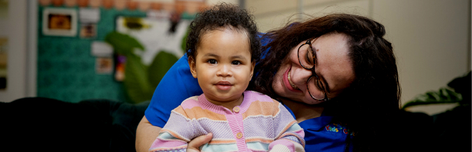 Column image Early learning centre educator holding toddler in classroom