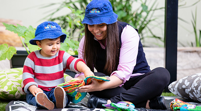 Carousel image Educator supporting a child during an interactive learning activity at Kids Club Childcare Centre in a calm and nurturing environment.