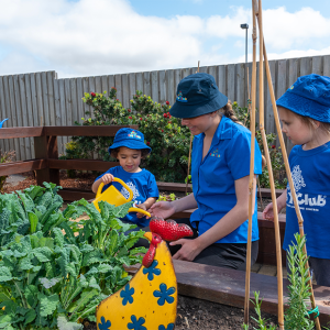 Column image Children gardening with an educator in an outdoor learning area at Kids Club