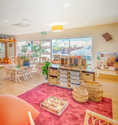 Column image Natural early learning centre classroom with timber storage units, sensory play materials, soft furnishings and bright open spaces for children.